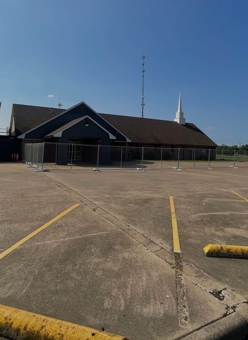 Temporary chain link fence panels on stands closing off a building entrance and parking lot